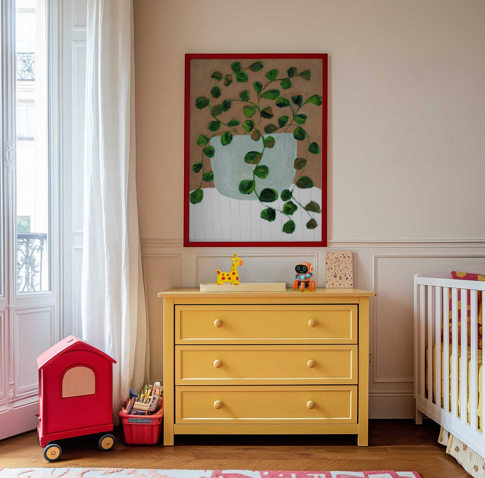 Inramad barntavla med växtillustration placerad ovanför byrå i ett stilrent och lugnt barnrum.