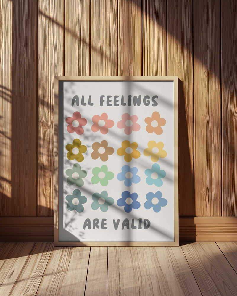 Inramad barntavla med färgglada blommor och texten "ALL FEELINGS ARE VALID" placerad på golvet mot en vägg med träpanel. En varm och ombonad känsla.