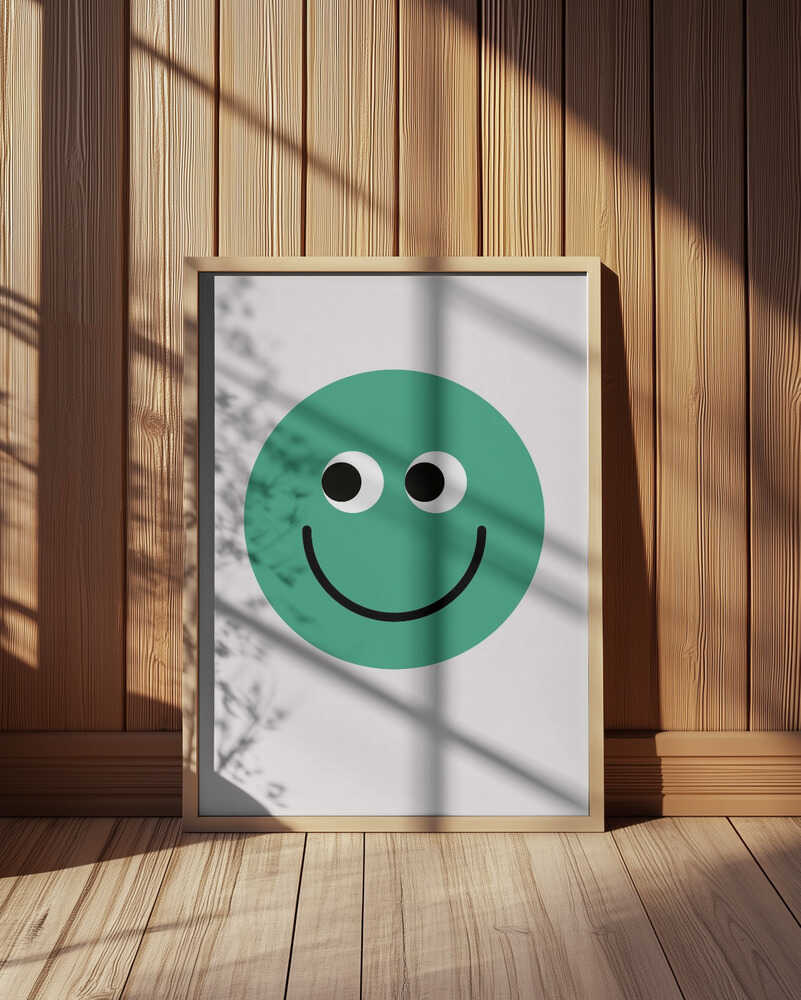Inramad barntavla med grön smiley placerad mot en vägg med träpanel där färgerna kontrasterar fint mot de naturliga tonerna.
