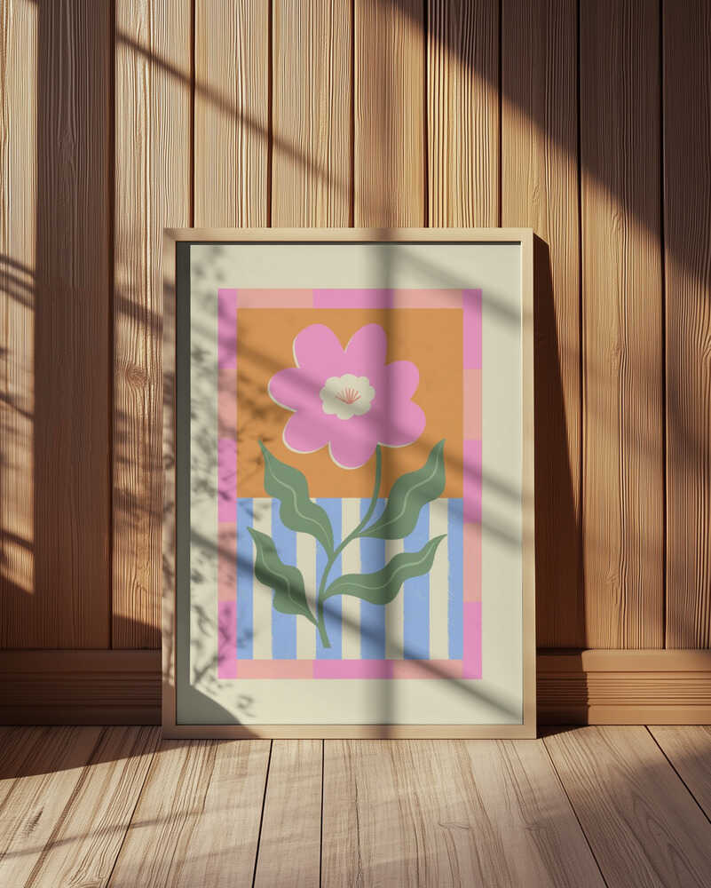 Inramad barnrumstavla med stor rosa blomma och färgrik bakgrund, placerad på golvet framför träpanel. En varm och livlig inredningsdetalj.