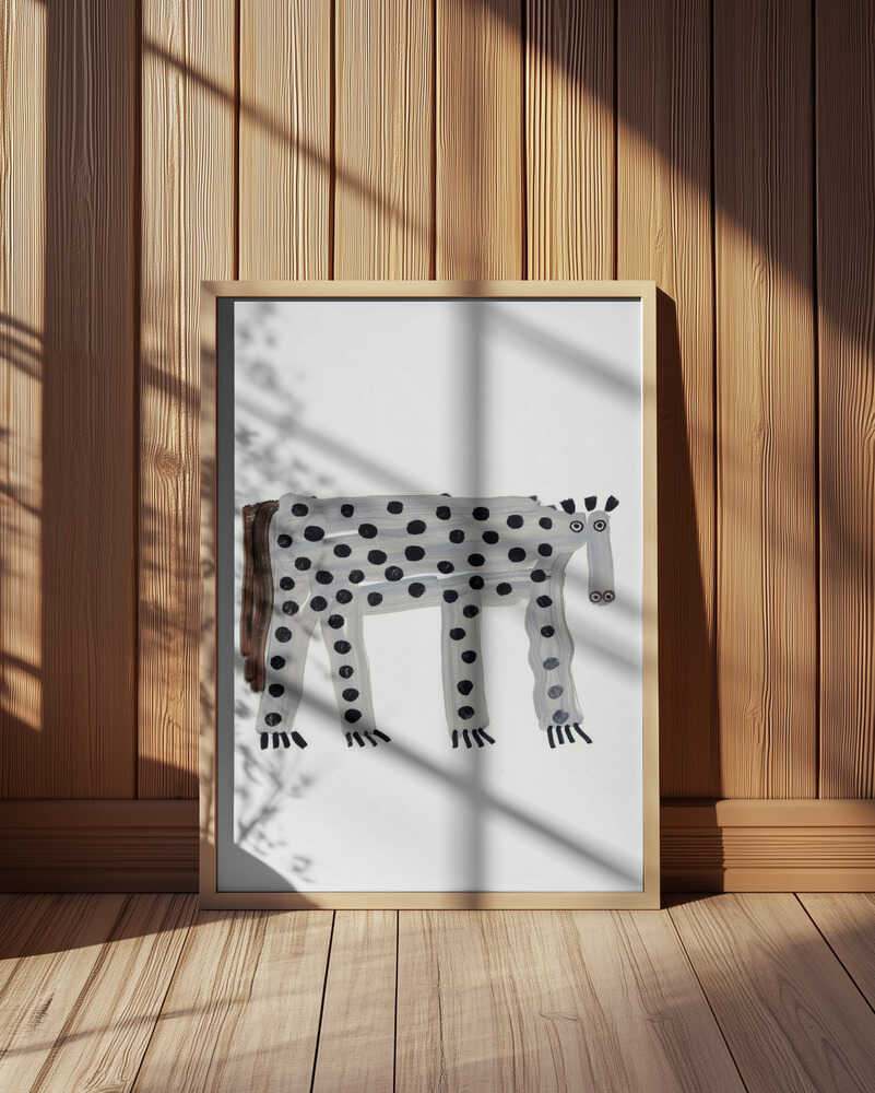 Inramad barntavla med prickigt fantasidjur, placerad framför träpanel och ger rummet ett charmigt och fantasifullt uttryck.