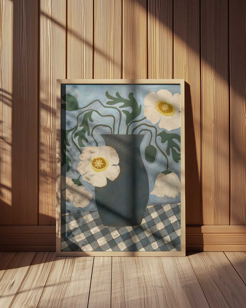 Inramad barntavla med blå vas och vita blommor placerad på golvet framför en vägg med träpanel.