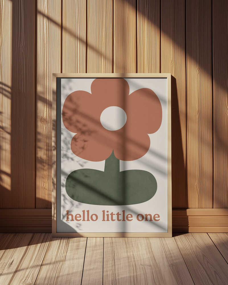 Inramad barntavla med blomma och texten "HELLO LITTLE ONE" placerad på golvet framför träpanel för en varm känsla.