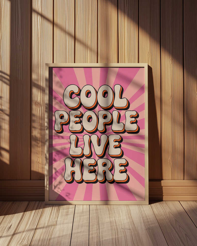 "Cool people live here" barntavla stående i en varm träpanelmiljö med solstrålar på väggen. Den rosa bakgrunden och de mjuka 70-talsinspirerade bokstäverna gör tavlan till en charmig detalj i barnrum och lekrum.