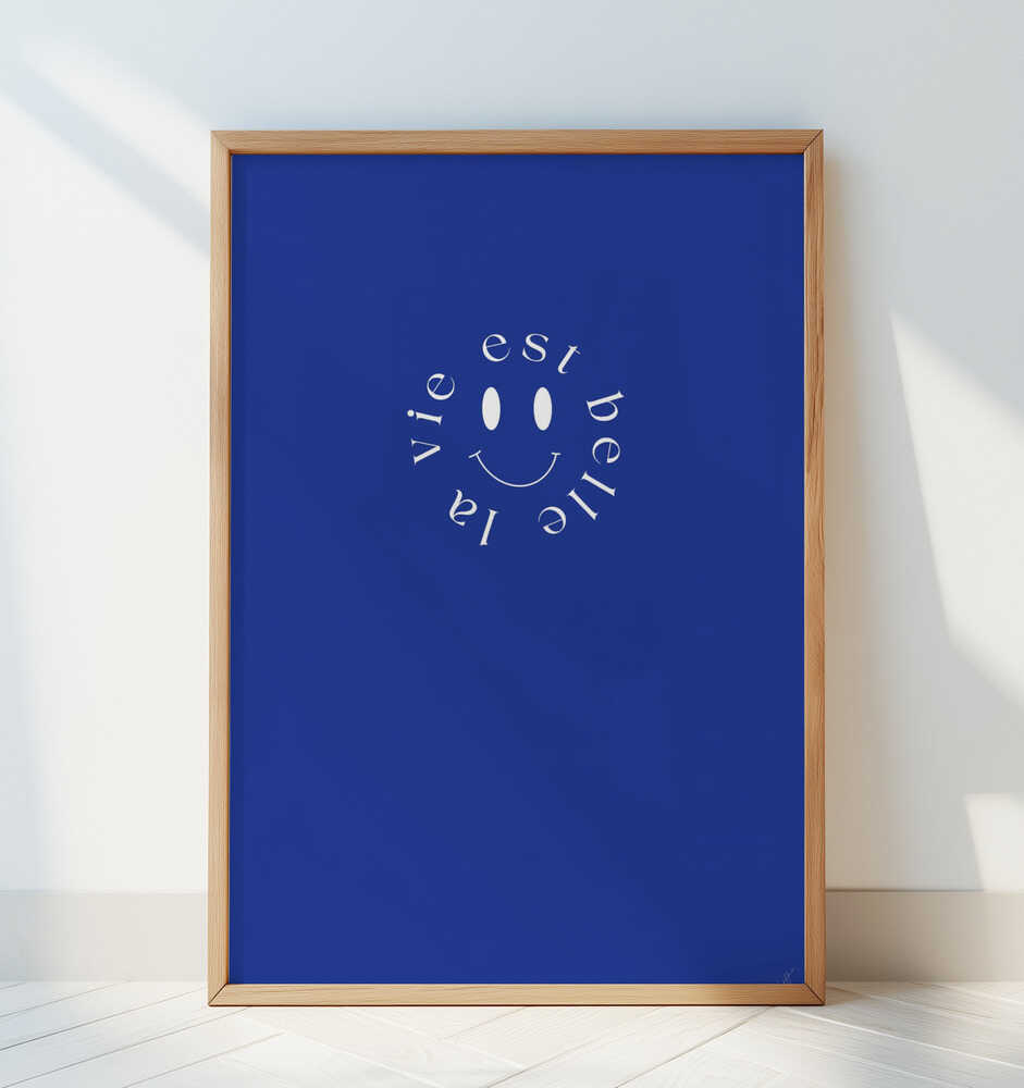 Barntavla med vit smiley och fransk text lutad mot en vit vägg, vilket framhäver det grafiska motivets rena form och färg.