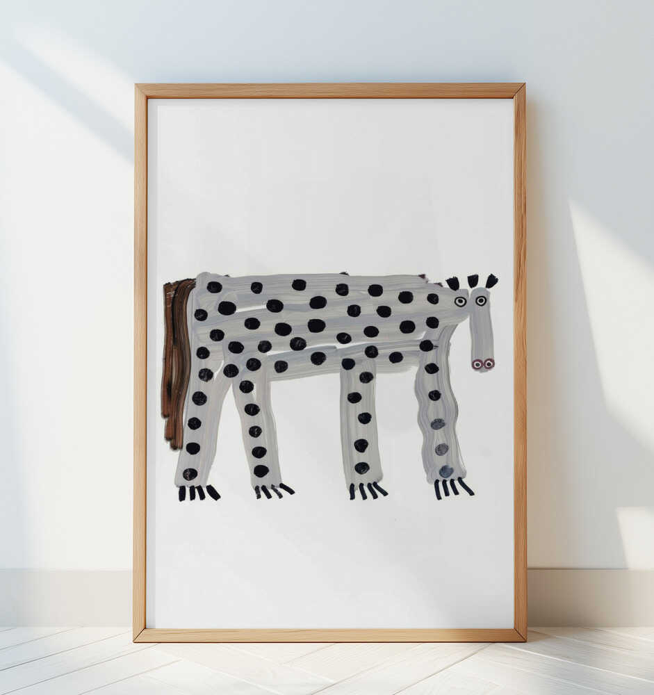 Inramad barntavla med prickigt djur, lutad mot en vit vägg för en ren, modern och lekfull känsla.