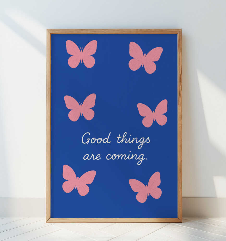 Barntavla med rosa fjärilar och texten "GOOD THINGS ARE COMING" lutad mot en ljus vägg med tydligt fokus på motivet.