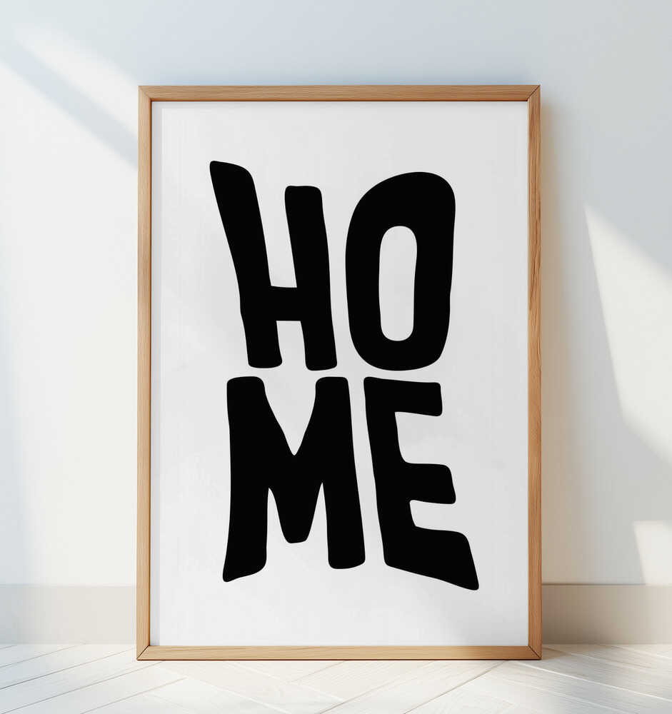 "HOME" barntavla inramad i träram, lutad mot en vit vägg i ett ljust skandinaviskt rum. Den minimalistiska designen framhävs av naturligt ljus och lugn inredning.