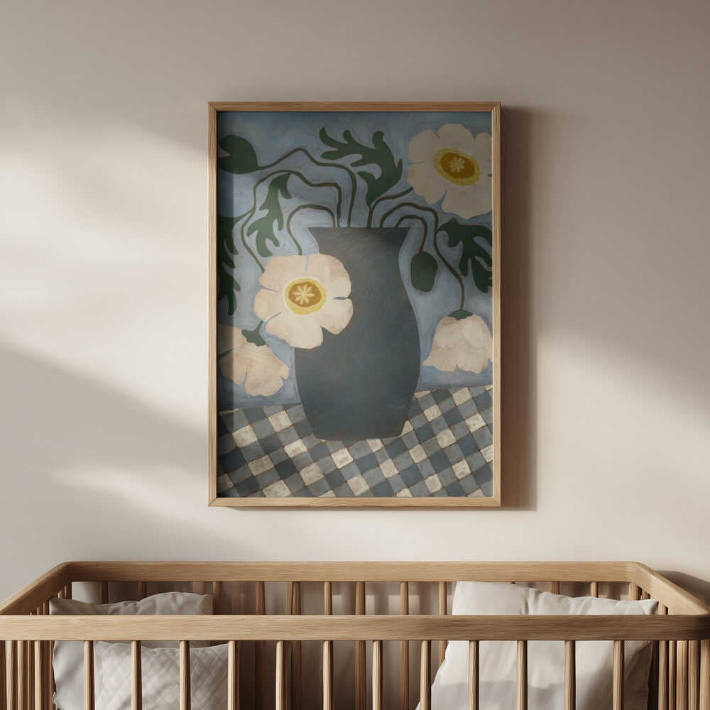 Inramad barntavla med blå vas och vita blommor upphängd ovanför spjälsängen i barnrummet.