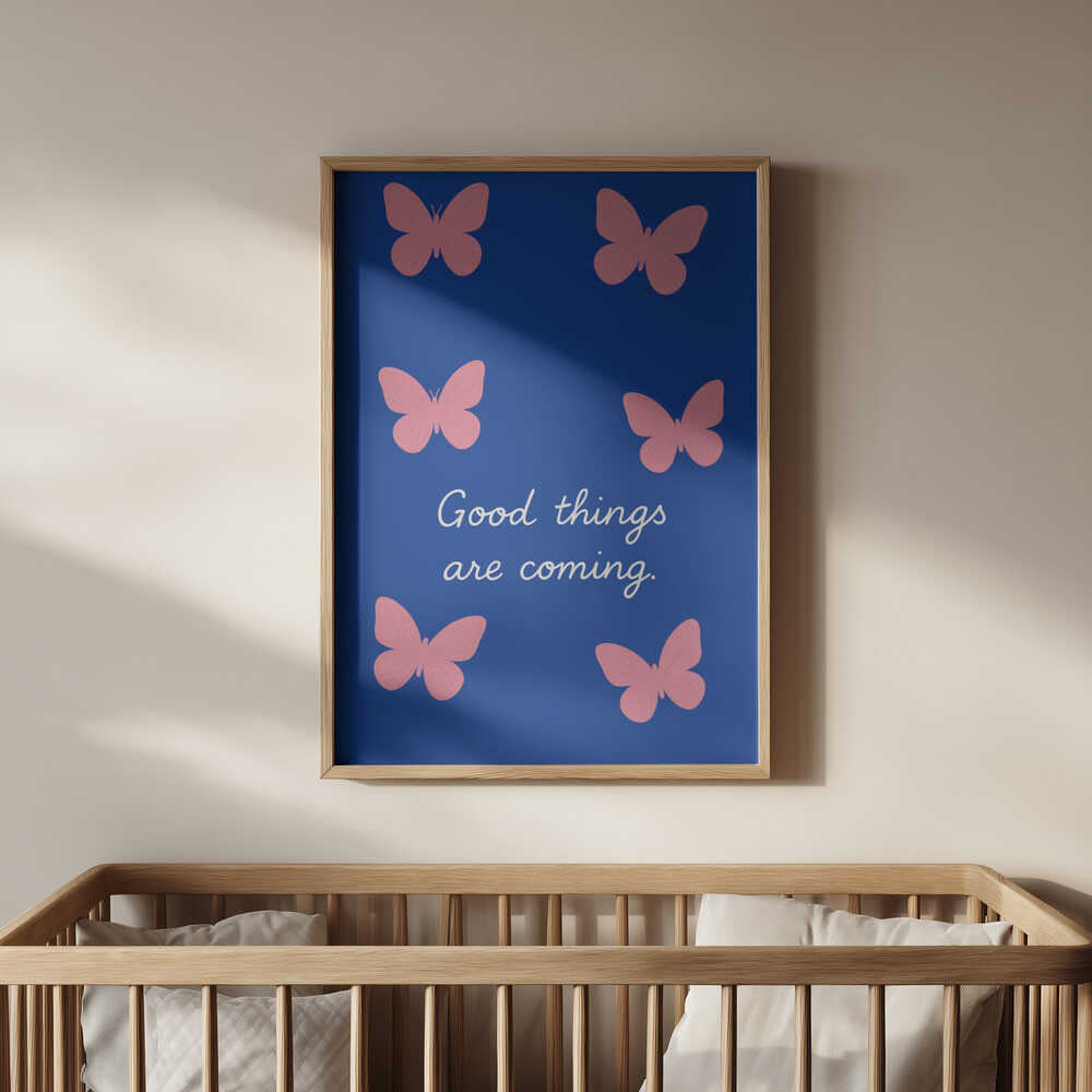 Barntavla med det blå och rosa fjärilsmotivet och texten "GOOD THINGS ARE COMING" upphängd ovanför spjälsäng för en trygg och drömsk känsla.