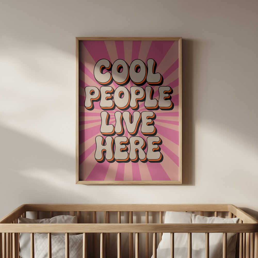 Barntavla med texten "Cool people live here" hängande ovanför en spjälsäng i ett ljust barnrum. Den rosa bakgrunden med retroinspirerade bokstäver i beige och orange ger rummet en lekfull och positiv känsla – perfekt väggkonst för barnrum.