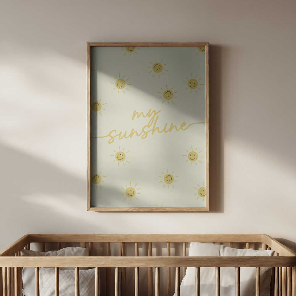 Inramad barntavla med solmönster och texten "my sunshine" ovanför spjälsängen som ger en trygg och solig känsla.