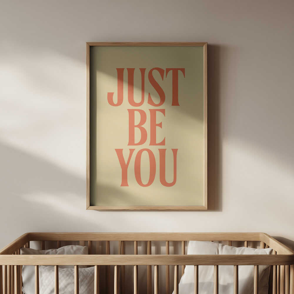 Inramad barnrumstavla med texten "JUST BE YOU" på gul bakgrund, placerad ovanför spjälsängen. En lugn och uppmuntrande detalj för barnrummet.